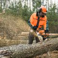 A chainsaw operator cutting through a log